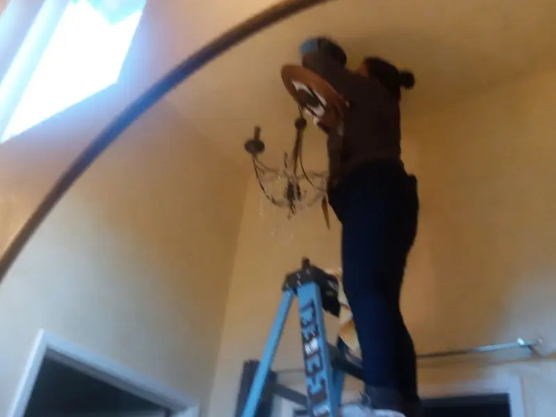 Electrician installing a chandelier in a Centerville residence